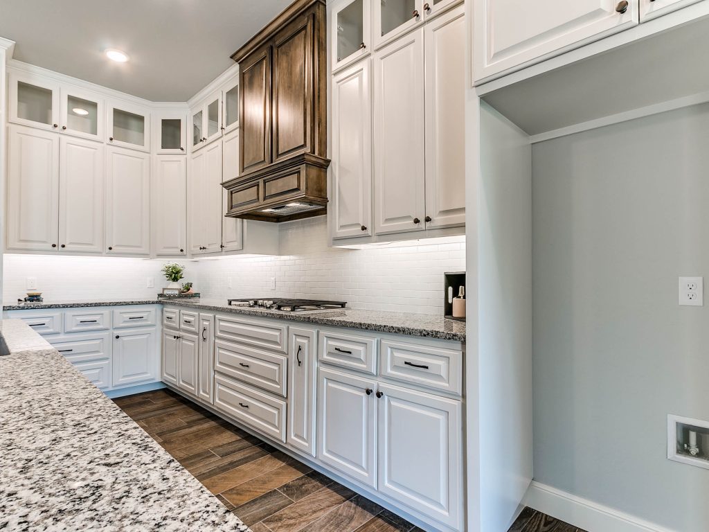 view of kitchen, stove with overhead vent and cabinets