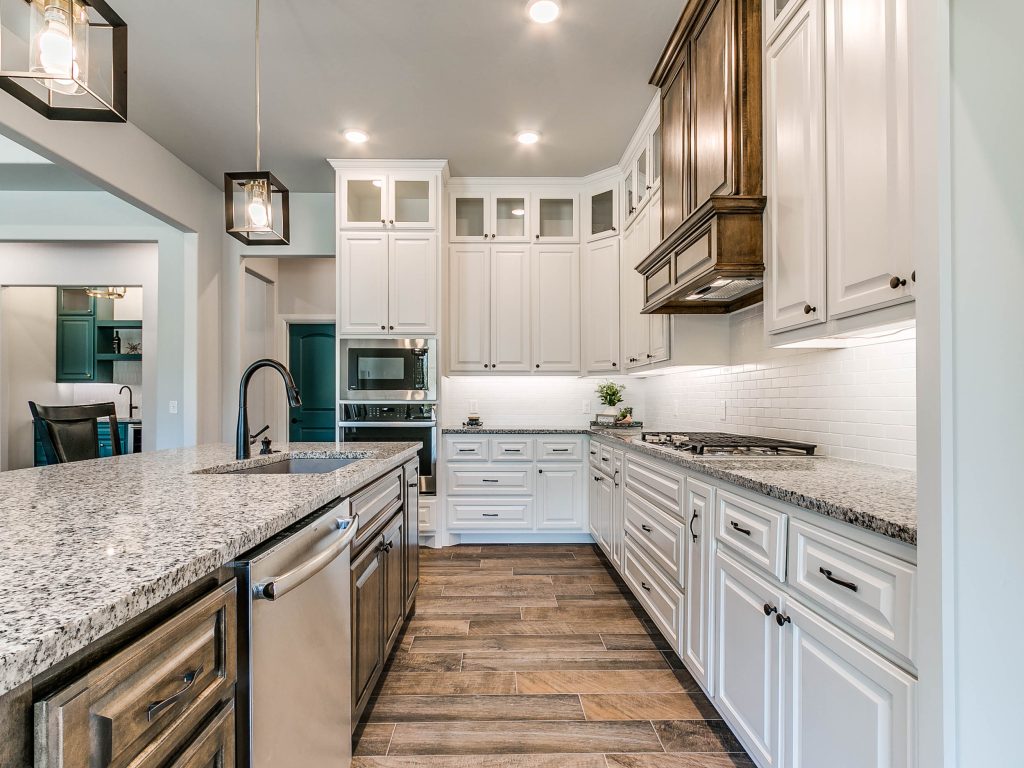 view of kitchen, island/breakfast bar with sink and dishwasher, stove with cabinets, overhead vents, oven, and microwave