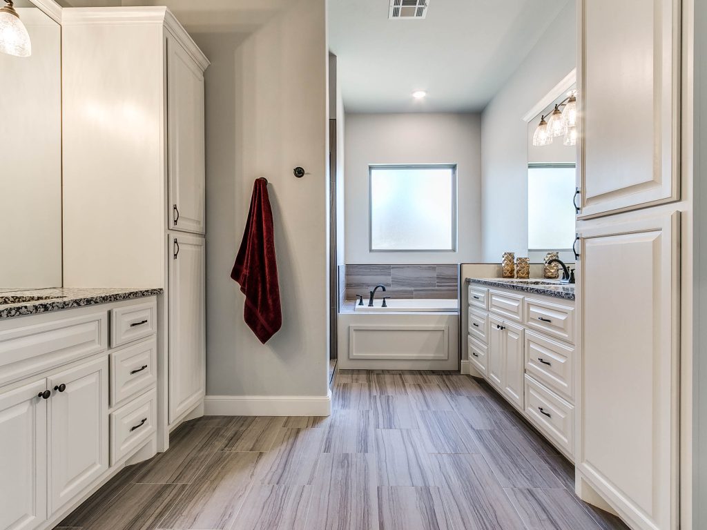 bathroom with two sinks, bathtub, and cabinet storage