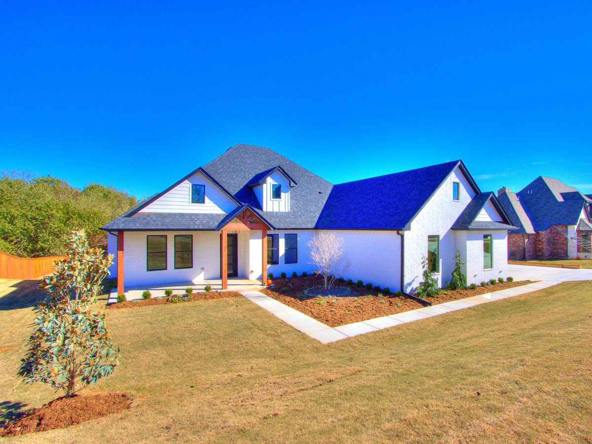 The front exterior of the light colored home with a dark colored roof.