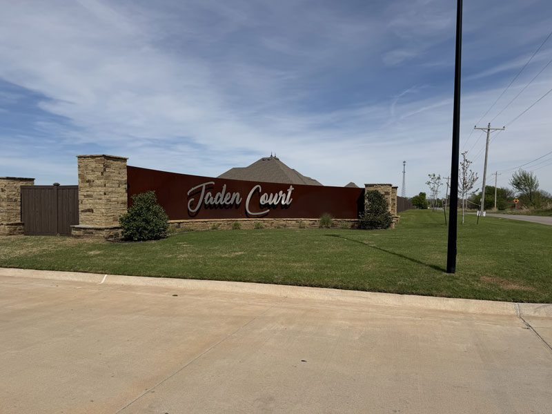 Neighborhood entrance. A wall with "Jaden Court" on the sign, with landscaping around it.